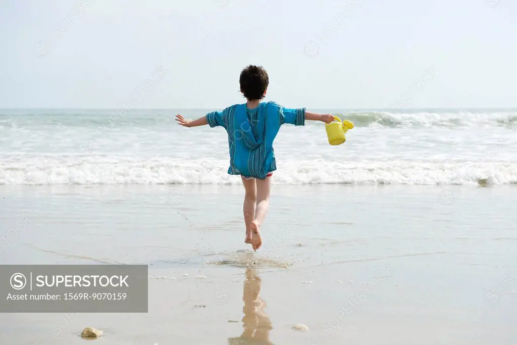 Boy running at the beach, rear view