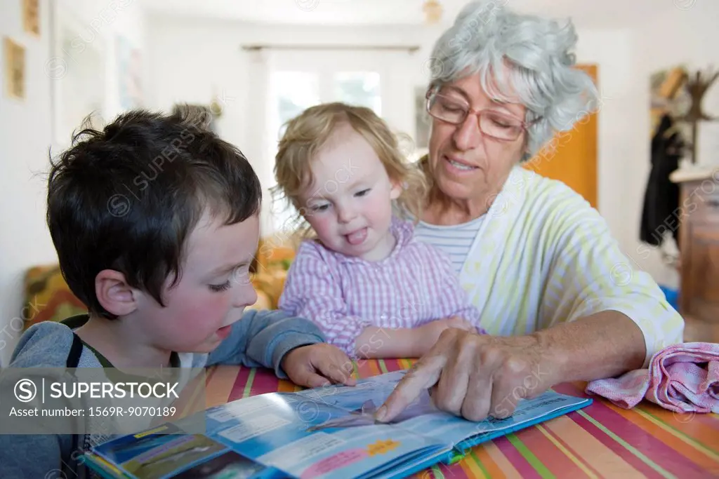 Grandmother reading book with young grandchildren