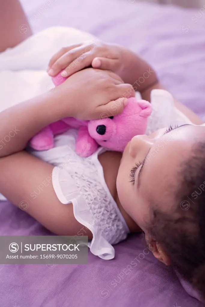 Little girl lying on bed with teddy bear