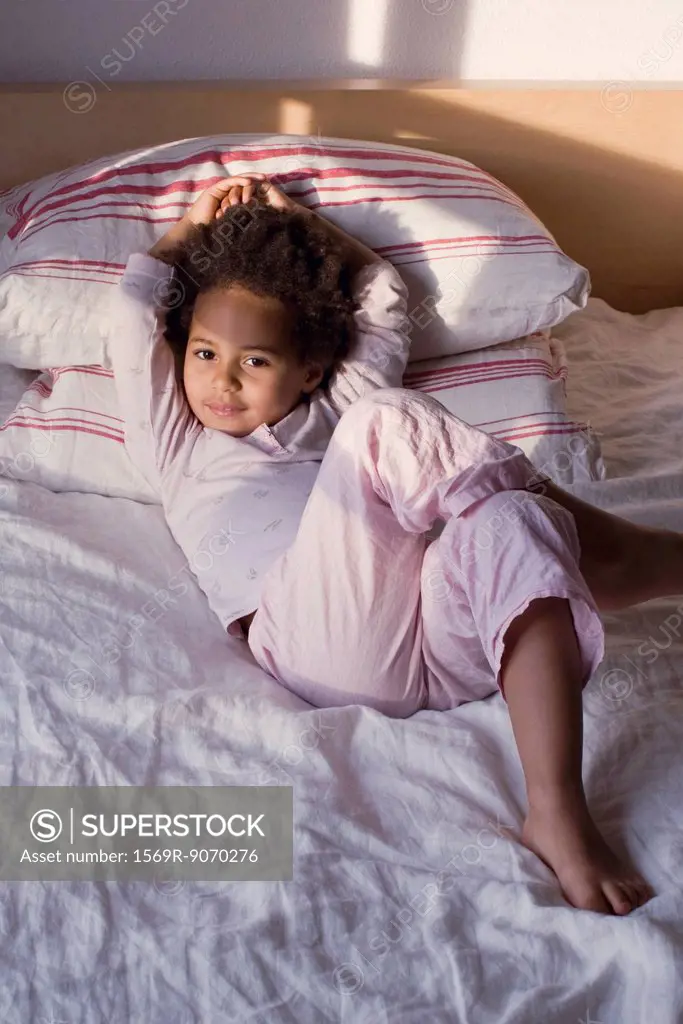 Little girl lying on bed in pajamas