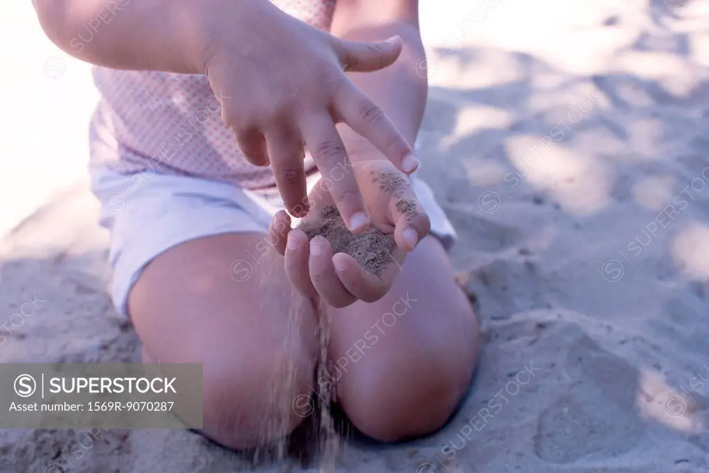 Little girl playing with sand in hands, mid section