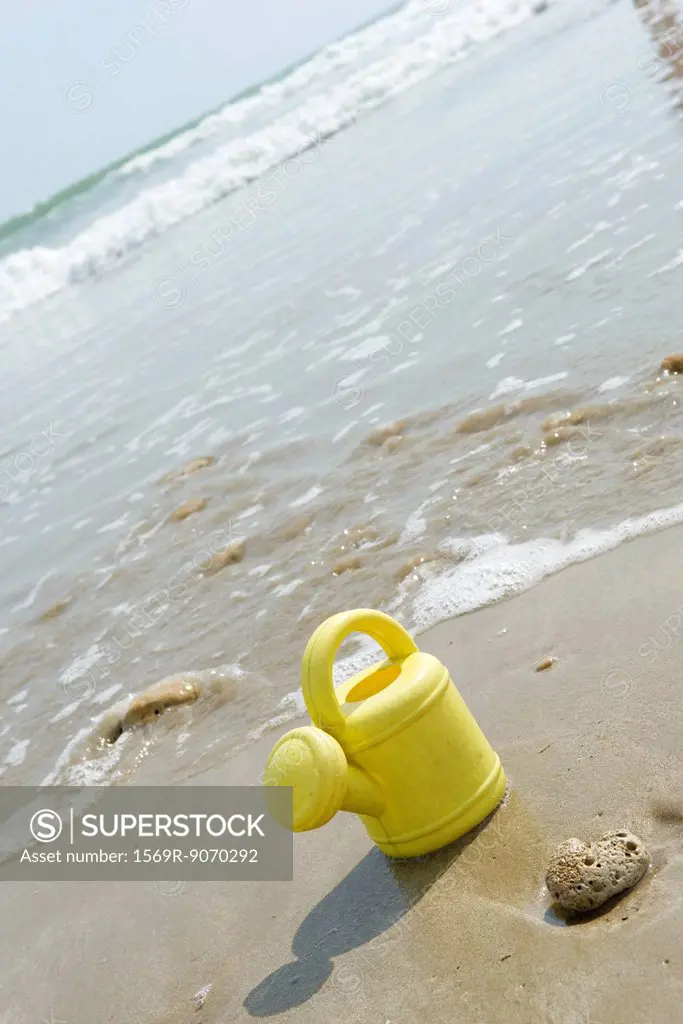 Toy watering can on beach