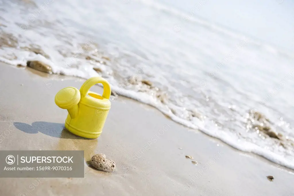 Toy watering can on beach