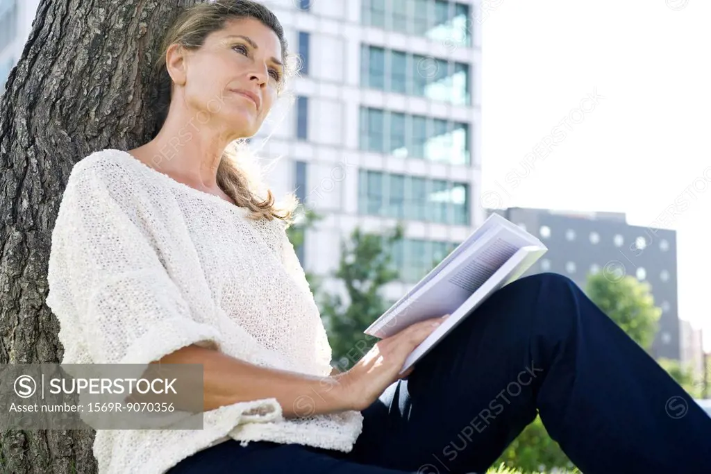 Woman with book looking away in thought