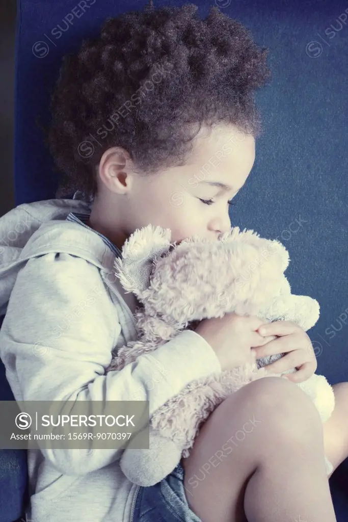 Little girl holding stuffed toy with eyes closed, portrait