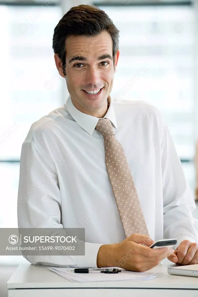 Businessman holding cell phone, portrait