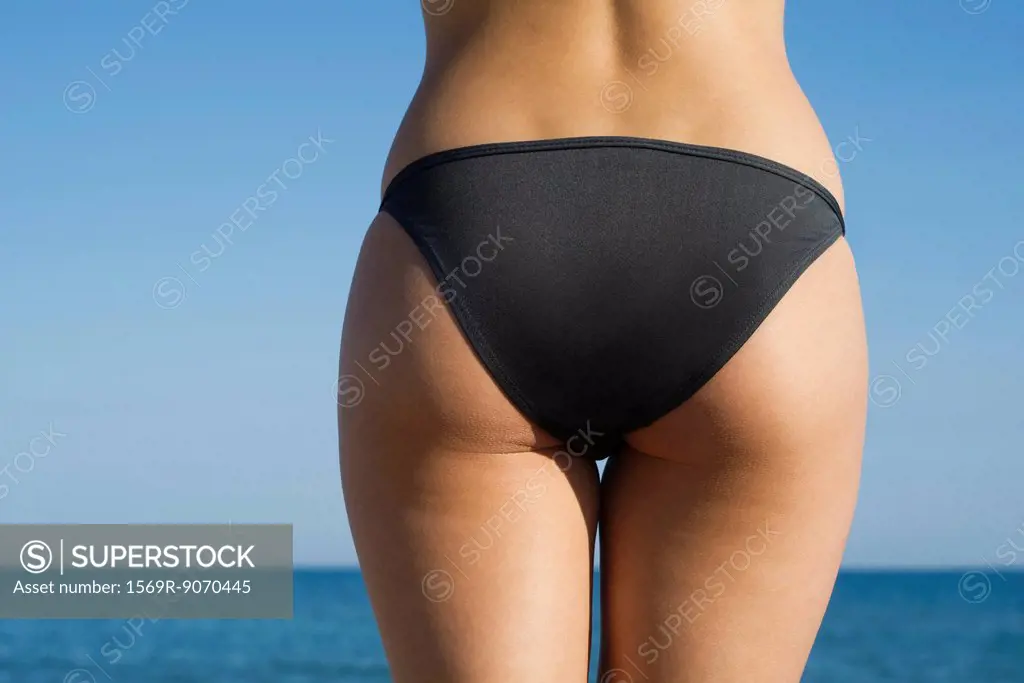Woman in bikini at the beach, cropped rear view