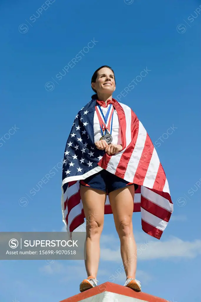Female athlete being honored on podium, wrapped in American flag