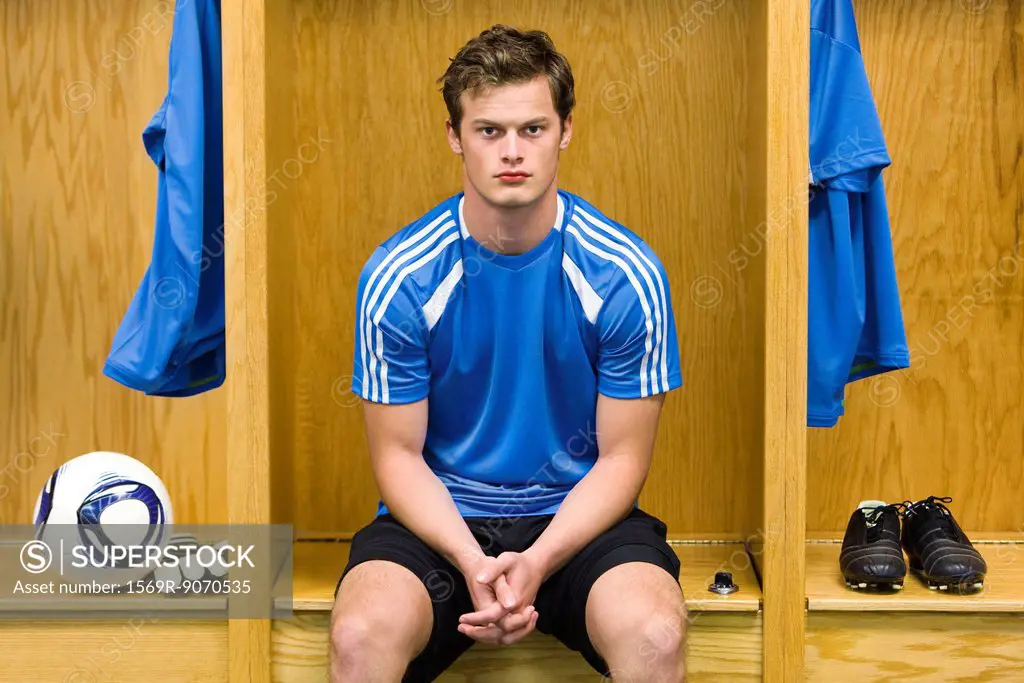 Young soccer player sitting in locker room, portrait