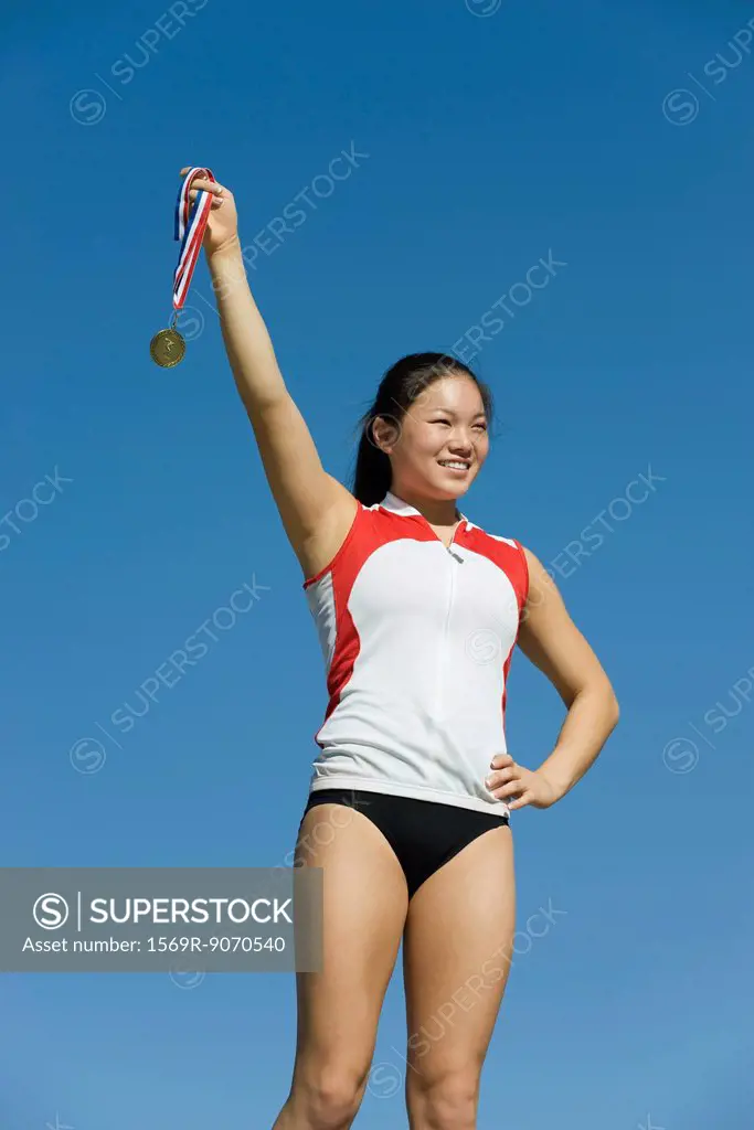 Female athlete being honored on podium, holding up medal