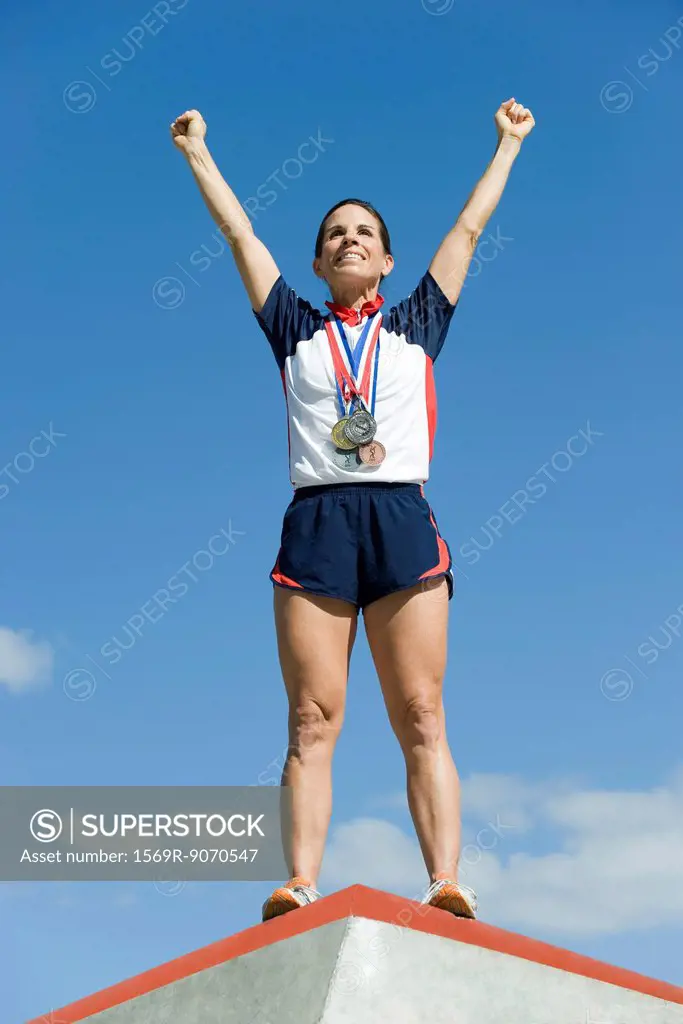 Female athlete standing on winner´s podium with arms raised in victory