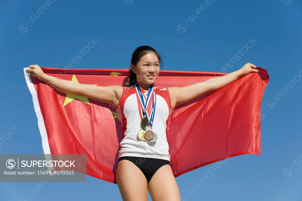 Female athlete on winner´s podium, holding Chinese flag