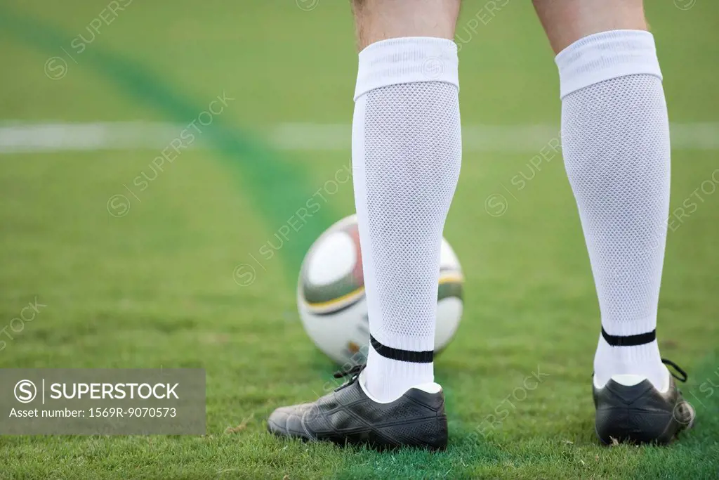 Soccer player standing on field, low section