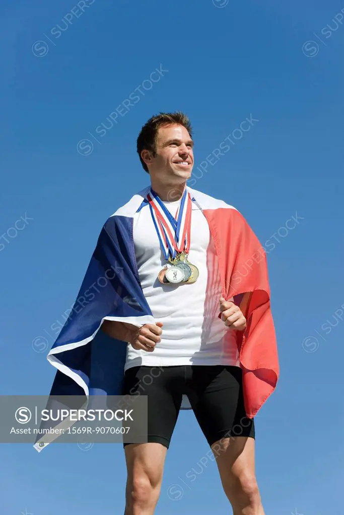 Male athlete being honored on podium, wrapped in French flag