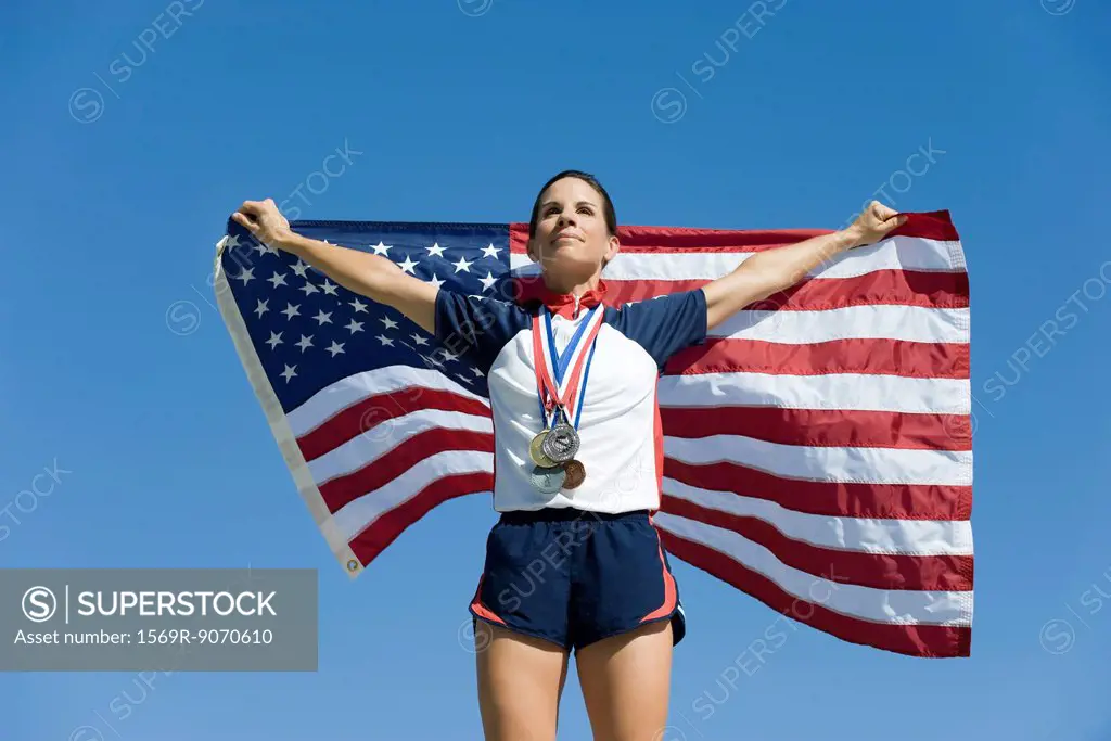 Female athlete being honored on podium, holding up American flag