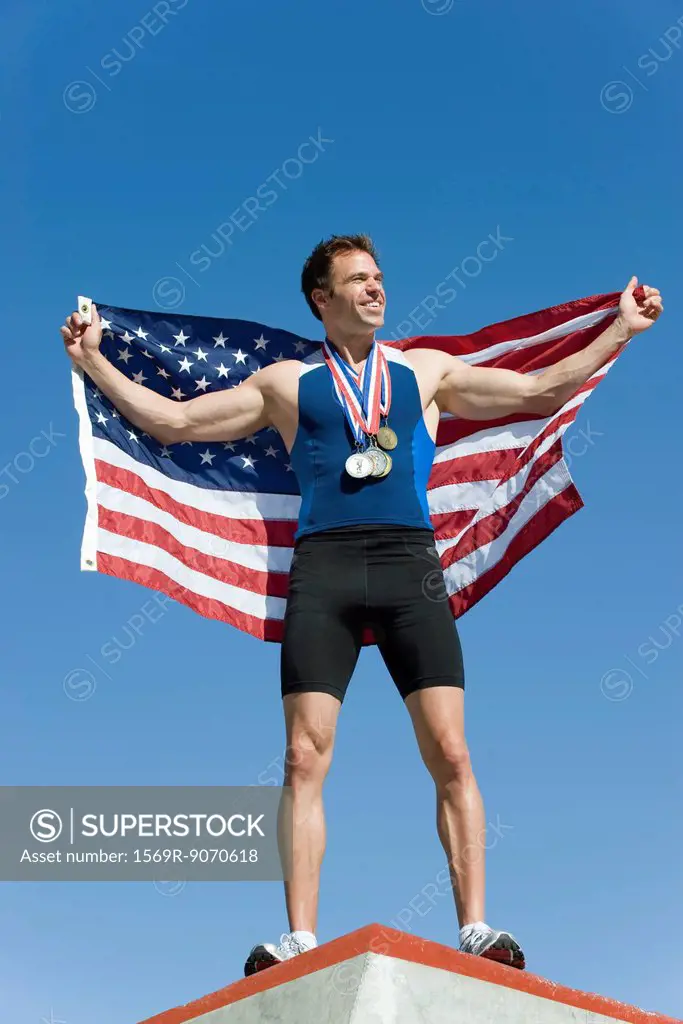 Male athlete on winner´s podium, holding up American flag