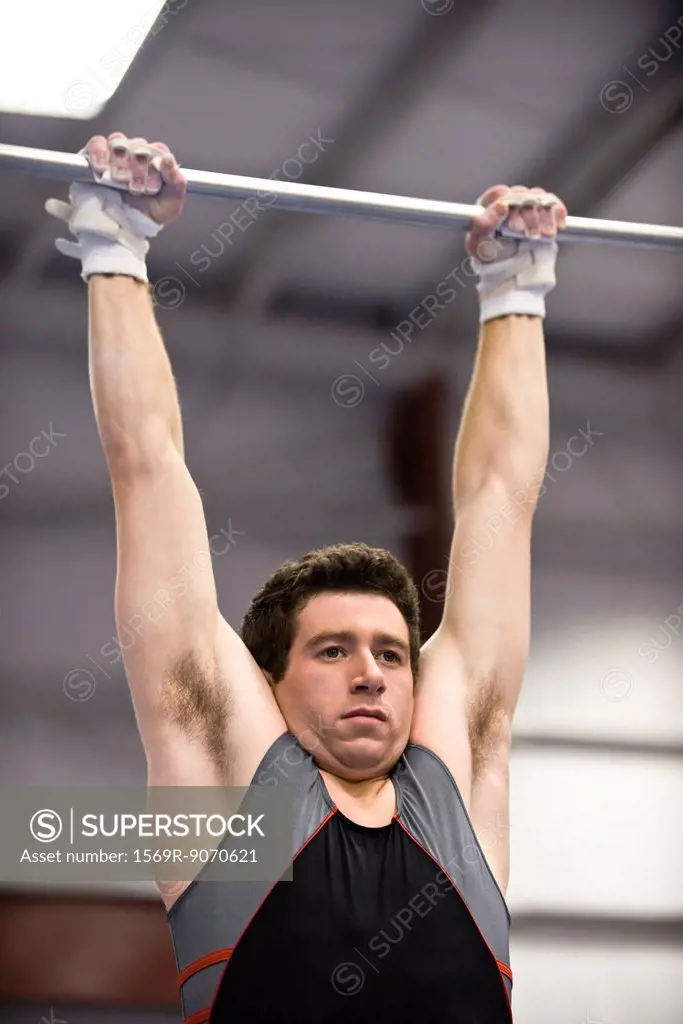 Male gymnast hanging from horizontal bar