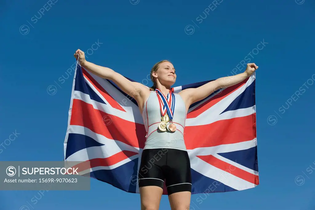 Female athlete being honored on podium, holding up British flag