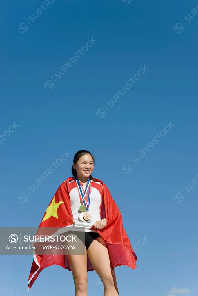 Female athlete on winner´s podium, wrapped in Chinese flag