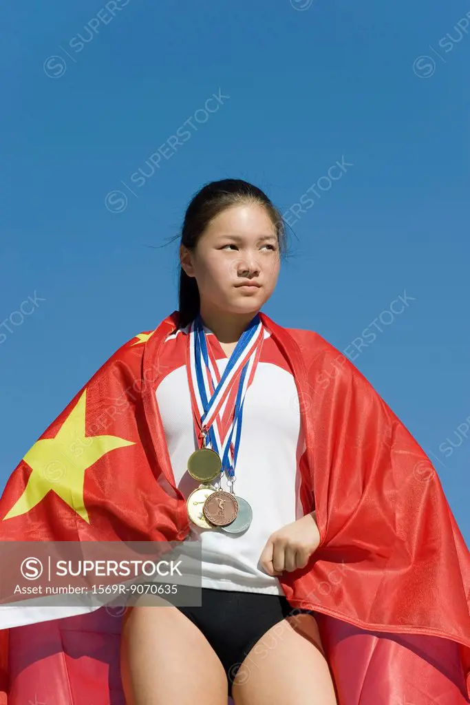 Female athlete on winner´s podium, wrapped in Chinese flag