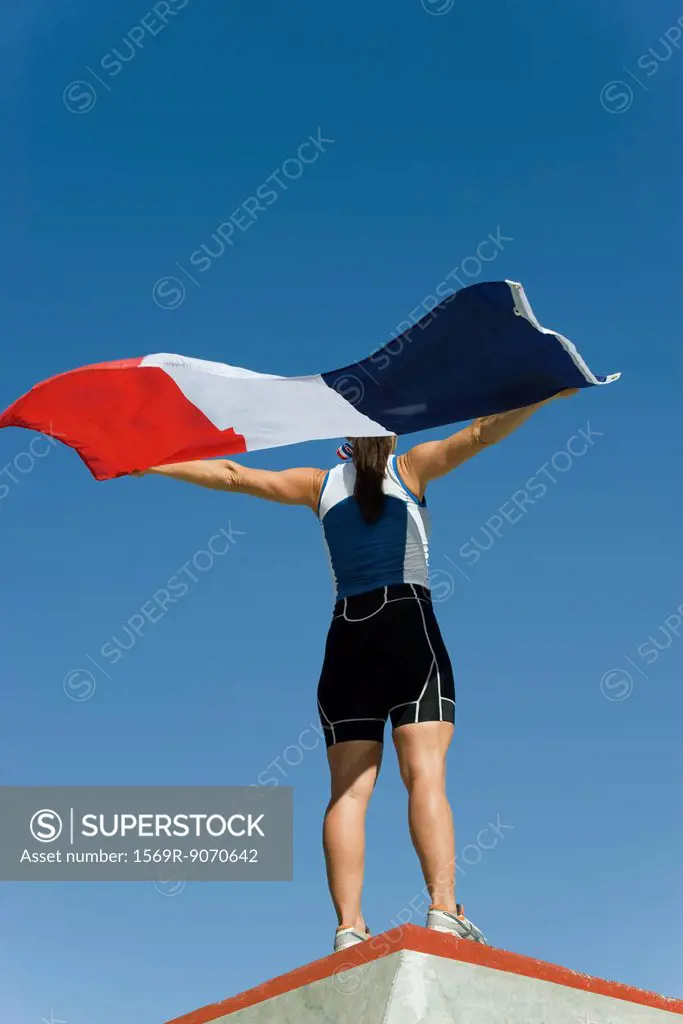 Female athlete on winner´s podium, holding up French flag