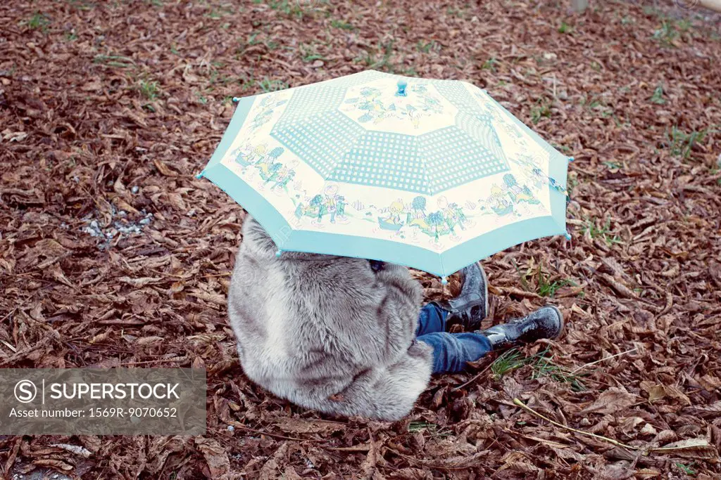 Child sitting under umbrella