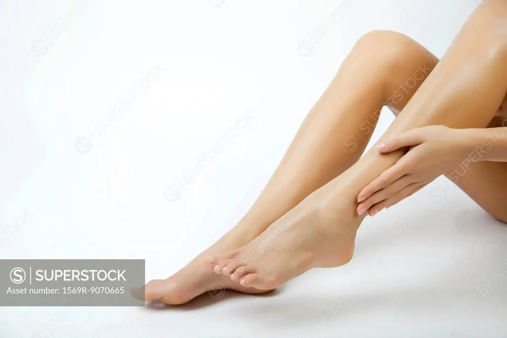 Woman moisturizing legs, cropped