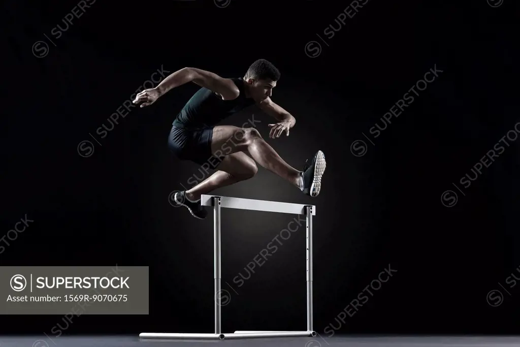 Male athlete clearing hurdle