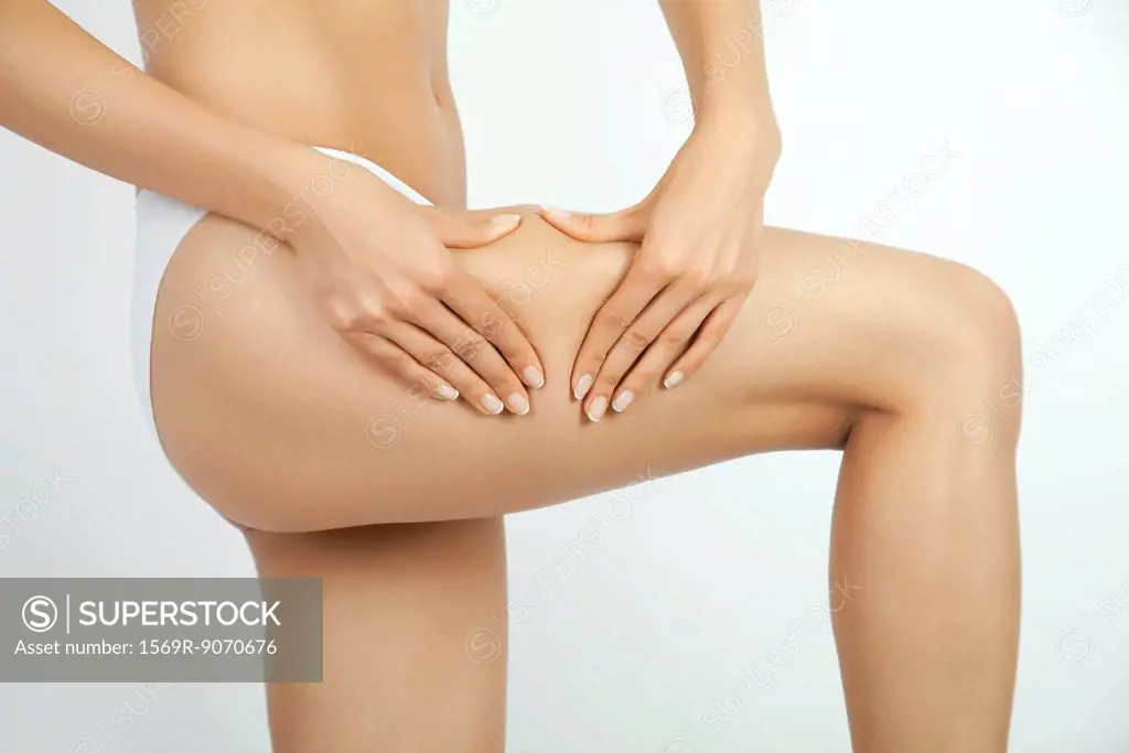 Woman pinching body fat on leg, cropped