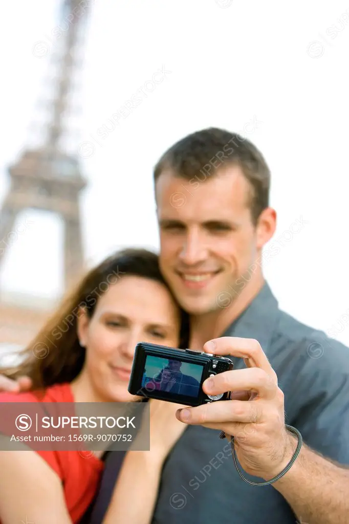Couple photographing selves in front of Eiffel Tower, Paris, France