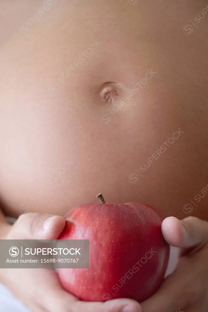 Pregnant woman holding apple, cropped