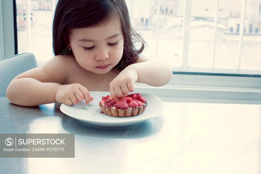 Little girl eating raspberry tart