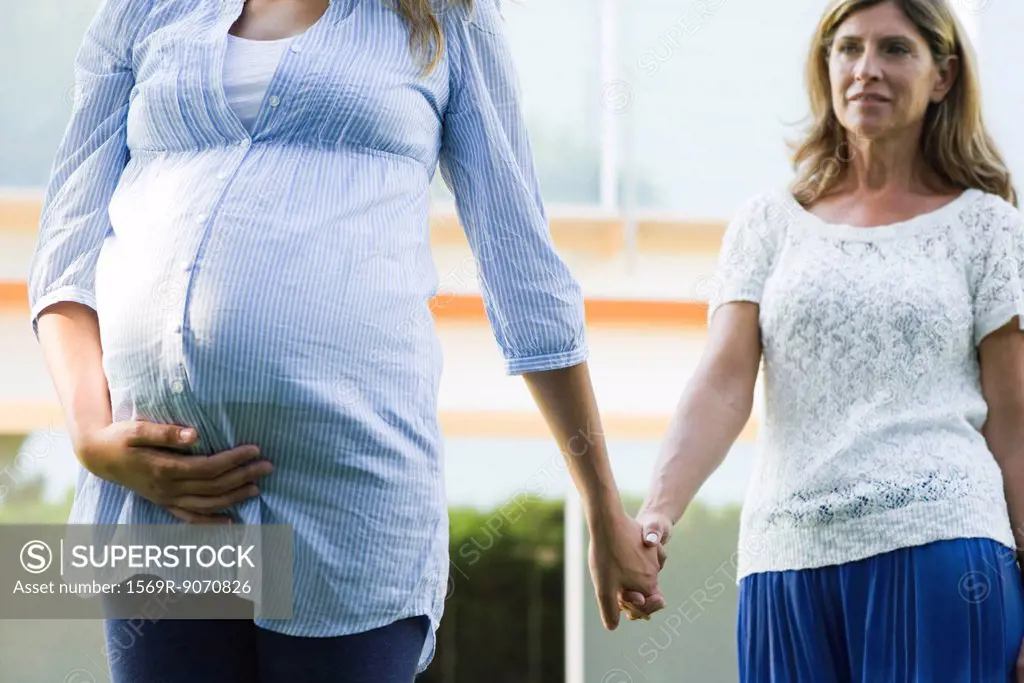 Mother and pregnant daughter holding hands