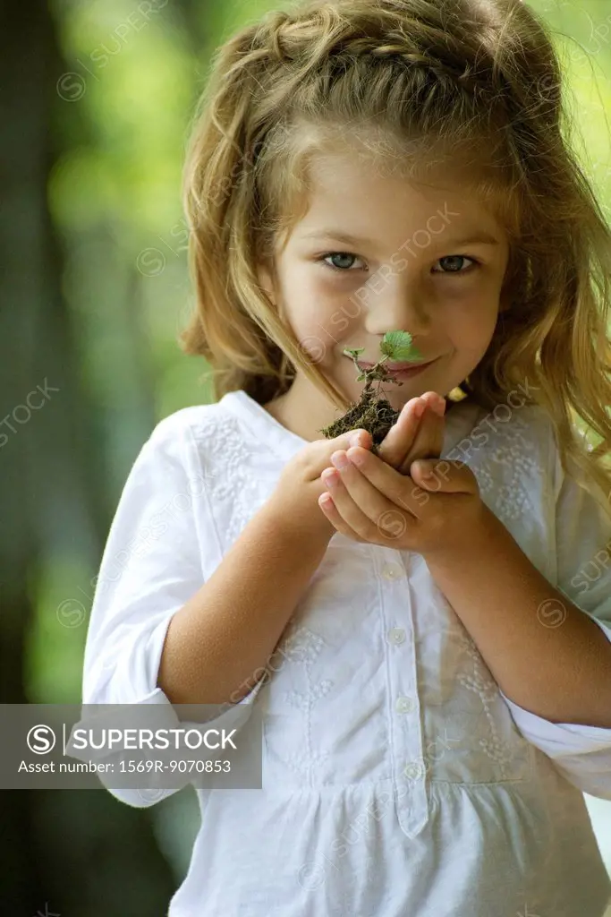 Girl holding seedling, portrait