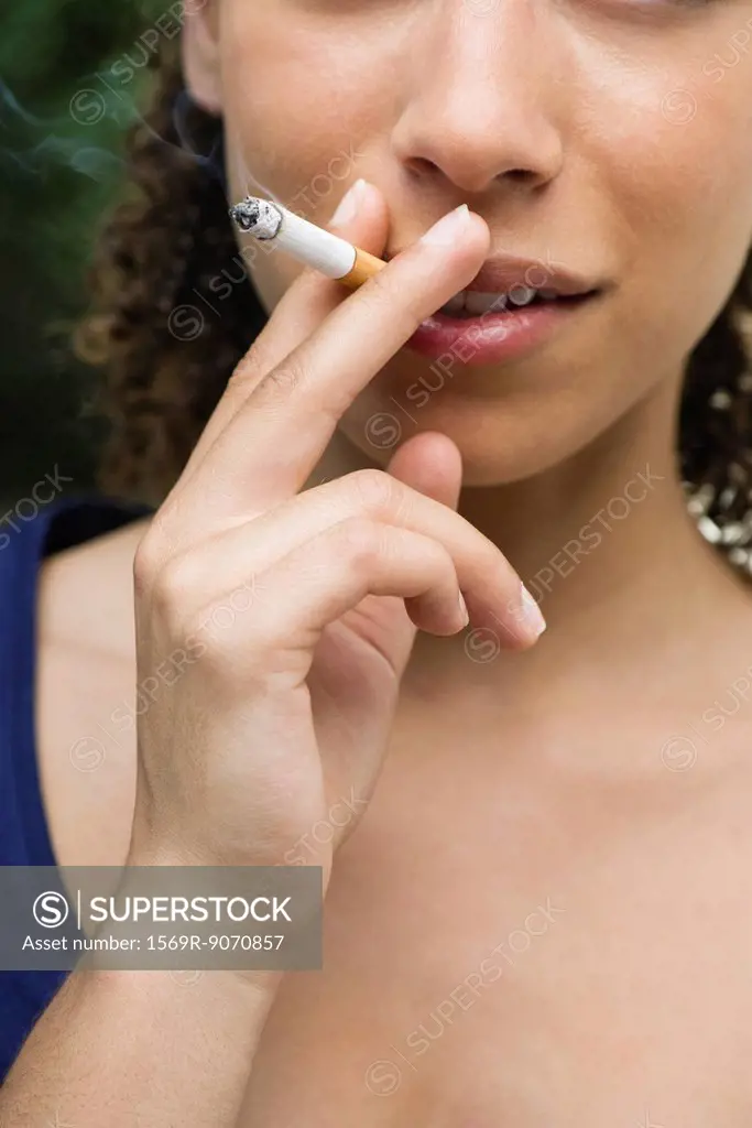 Young woman smoking cigarette, cropped