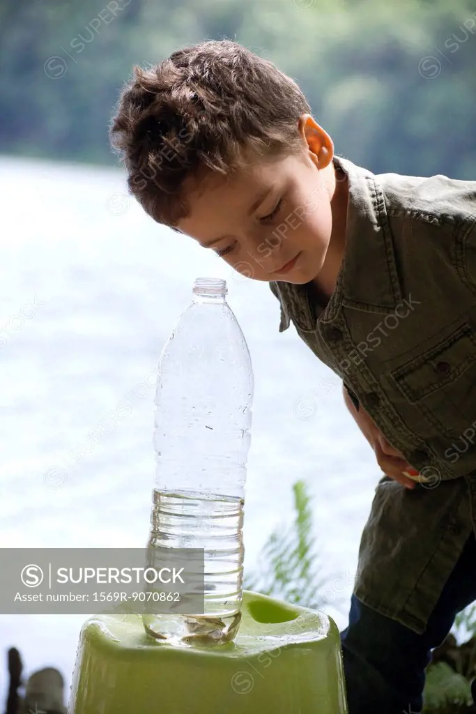 Boy looking at fish in water bottle