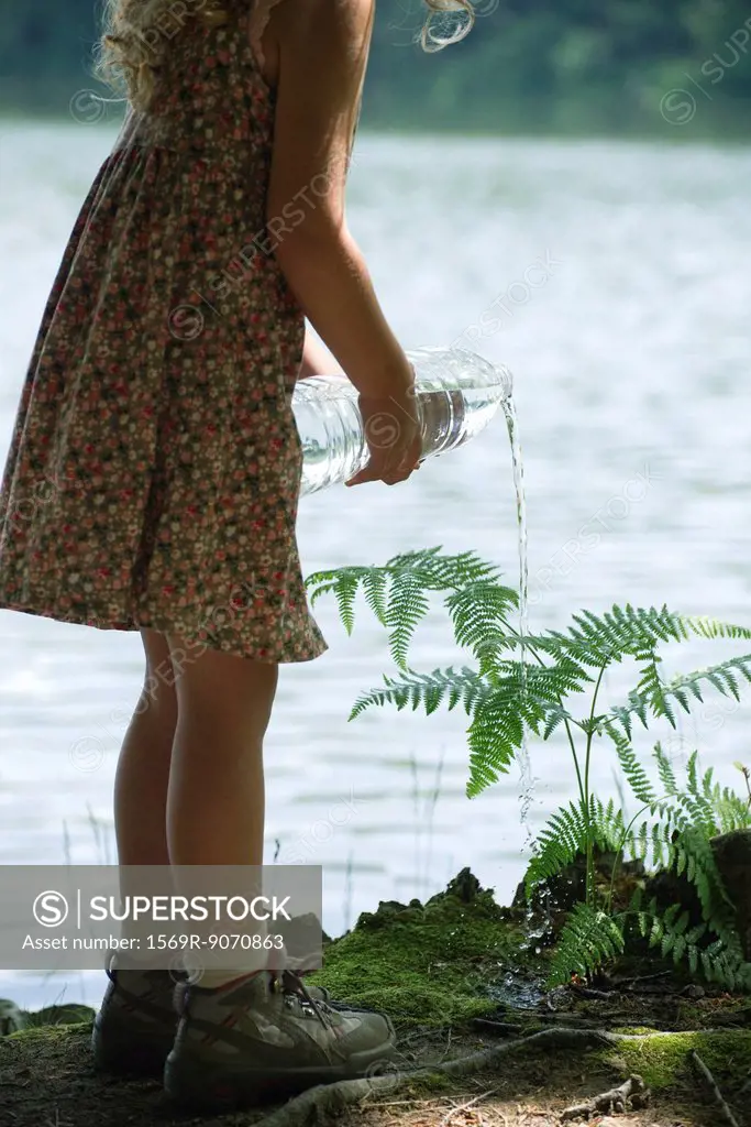 Girl watering plant with bottle of water