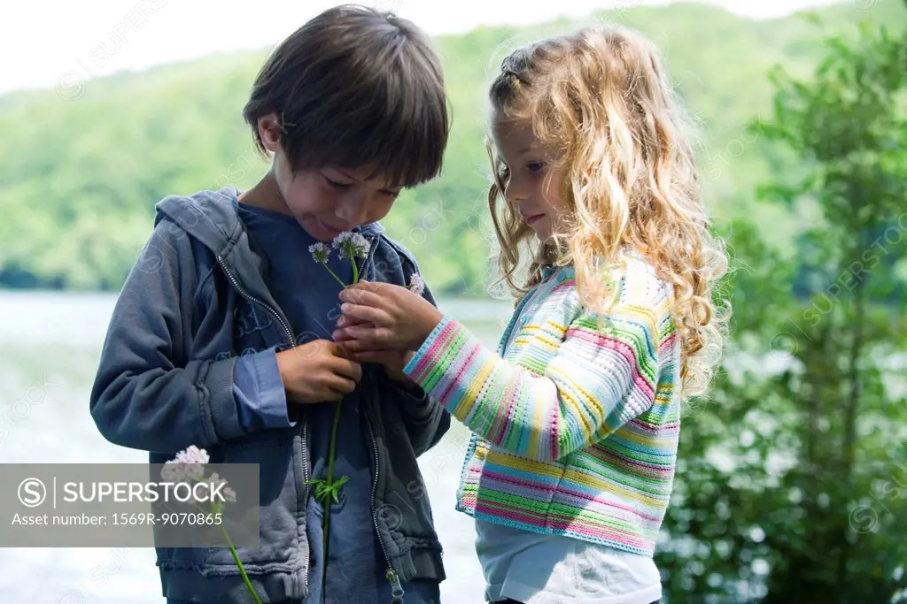 Children smelling wildflowers together outdoors