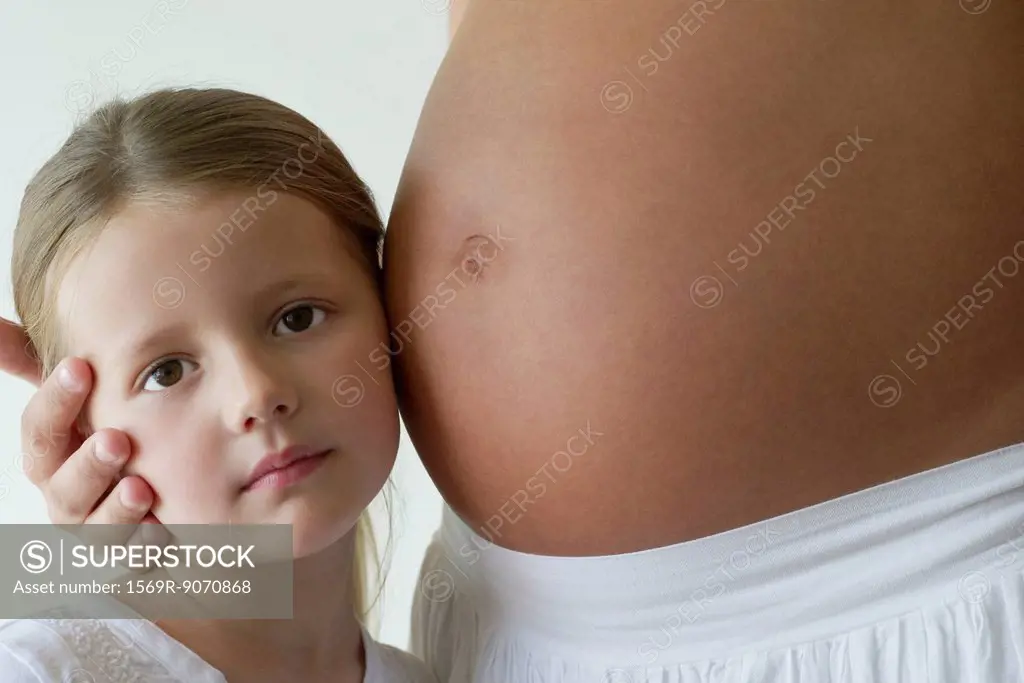 Girl listening to mother´s pregnant belly