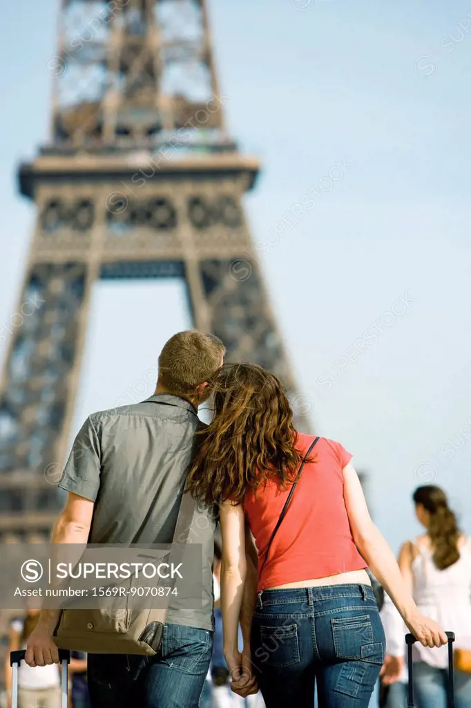 Tourist couple walking hand in hand toward Eiffel Tower, Paris, France
