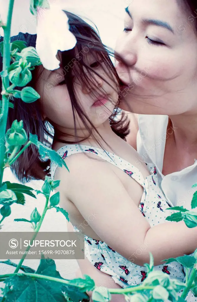 Mother kissing little girl´s cheek
