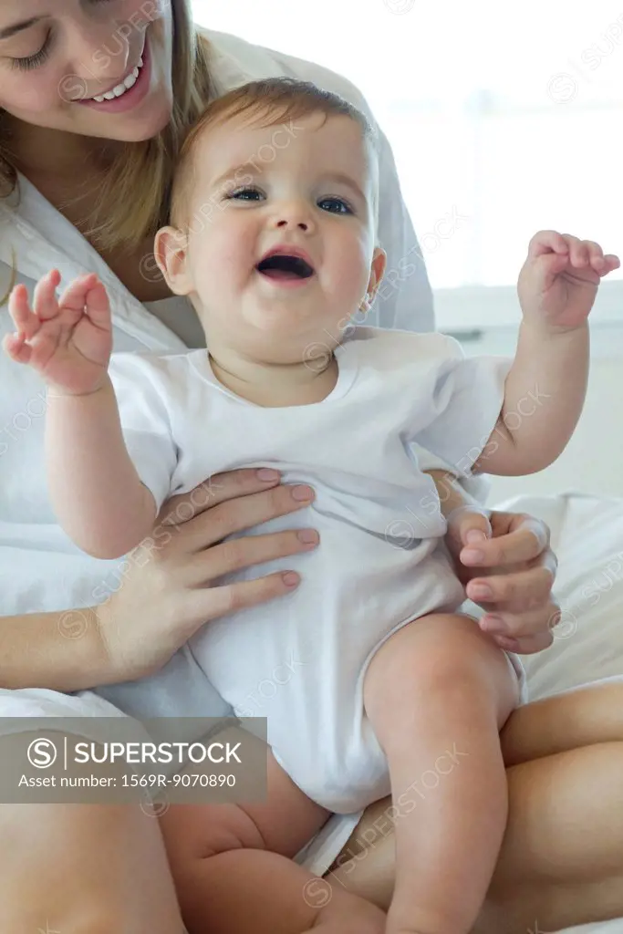 Baby sitting on mother´s lap, laughing