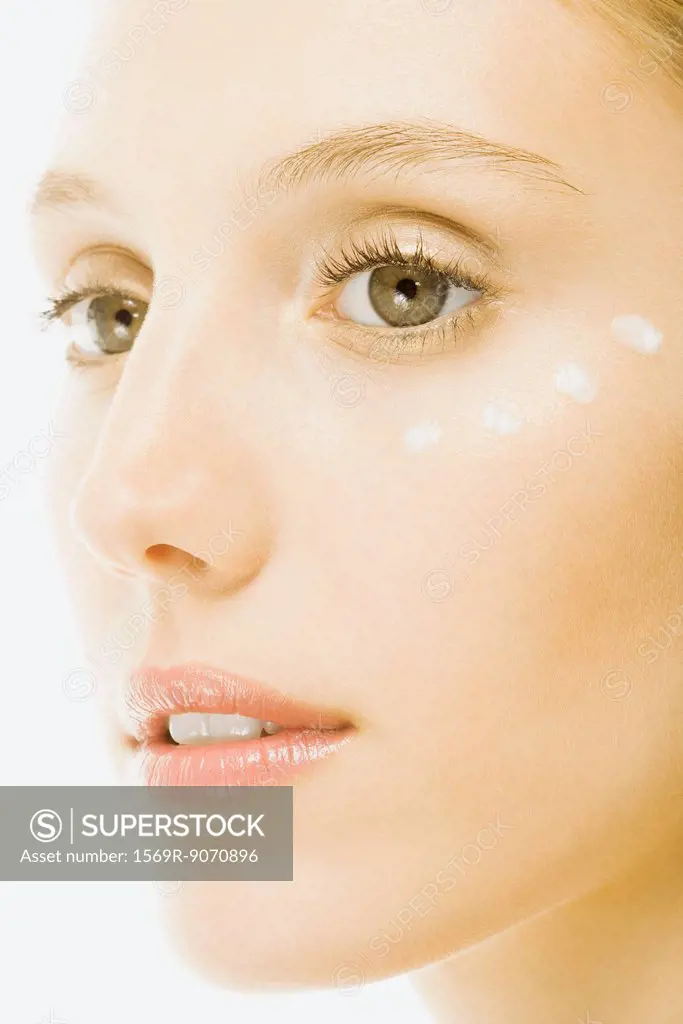 Woman with dots of undereye cream applied beneath eye, close_up of face