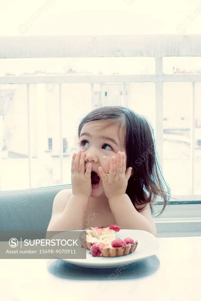 Little girl with surprised expression, hands on cheeks