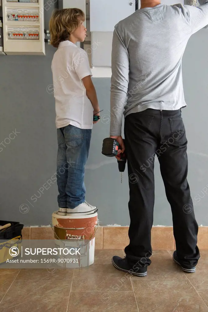 Boy watching father doing home improvement
