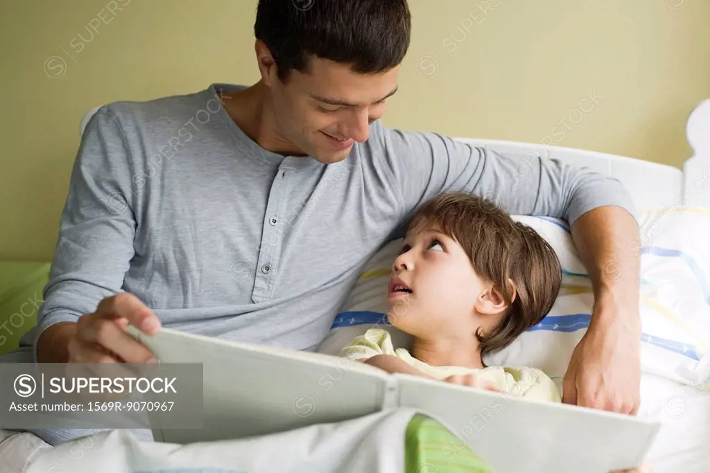 Father and son reading book together