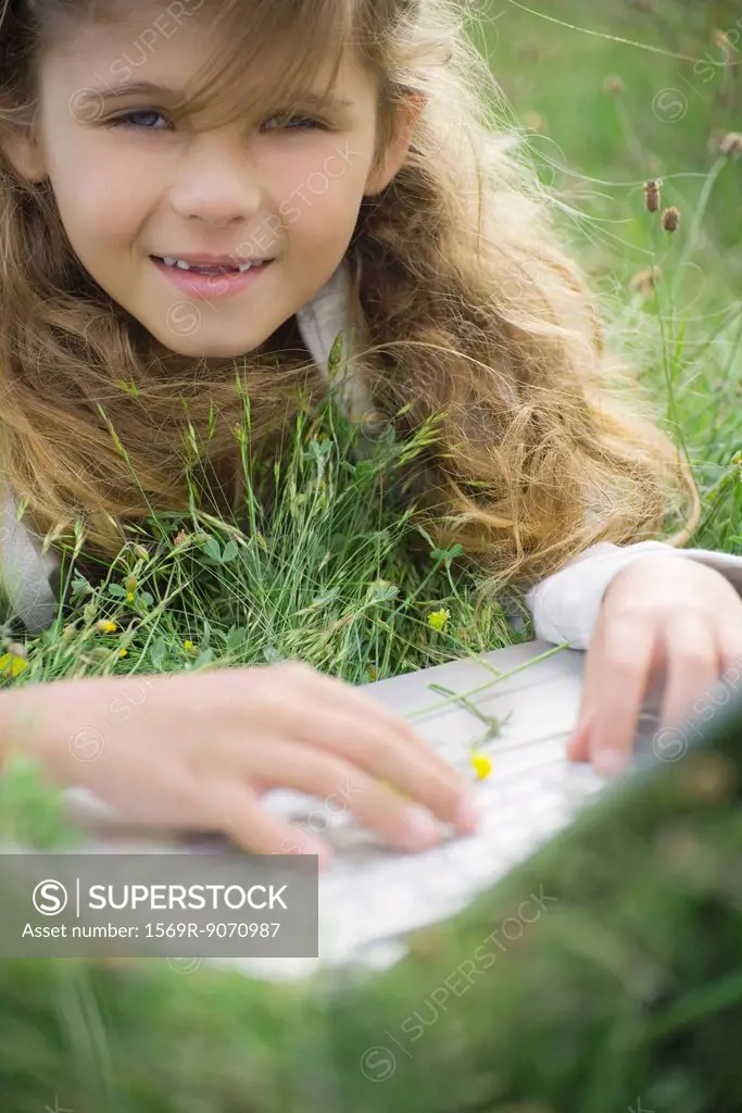 Girl lying in grass, using laptop computer, portrait