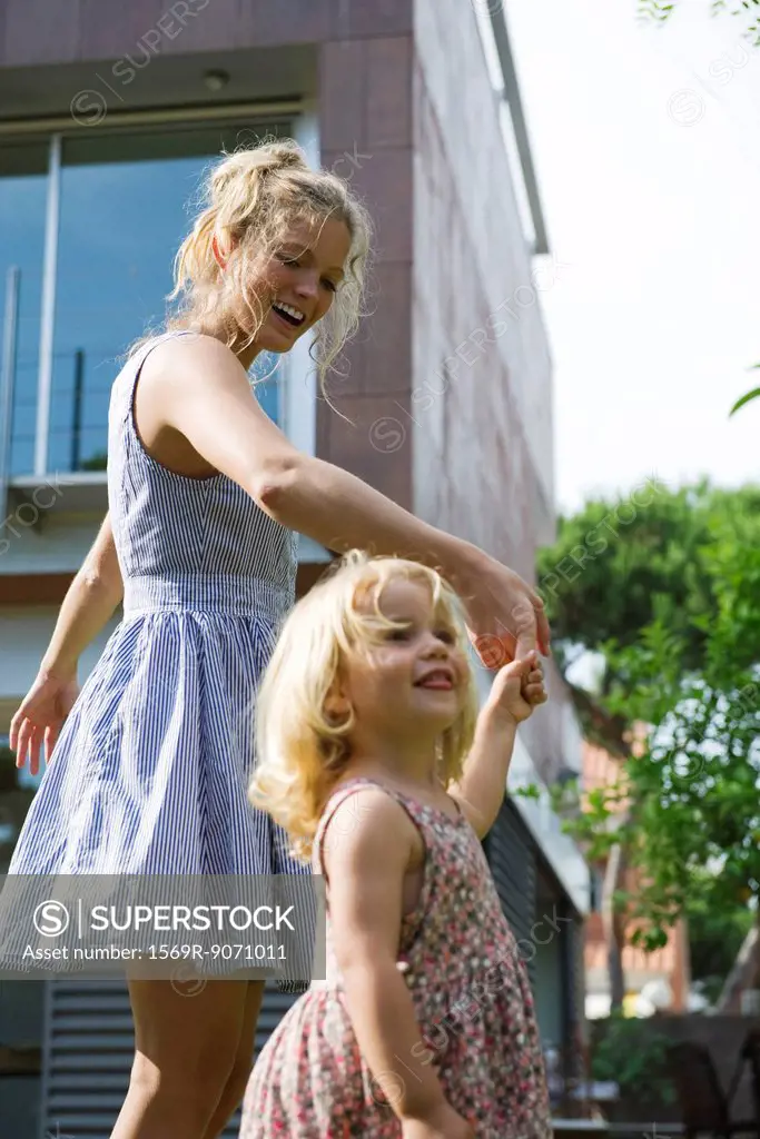 Mother and young daughter walking hand_in_hand outdoors