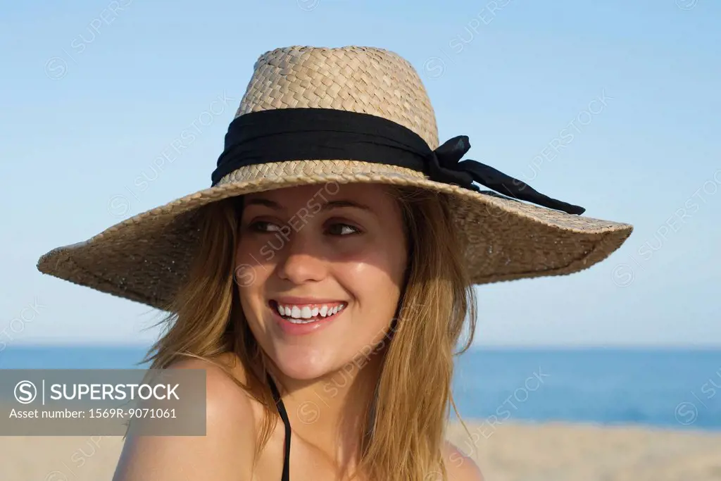 Woman wearing sun hat at the beach, portrait