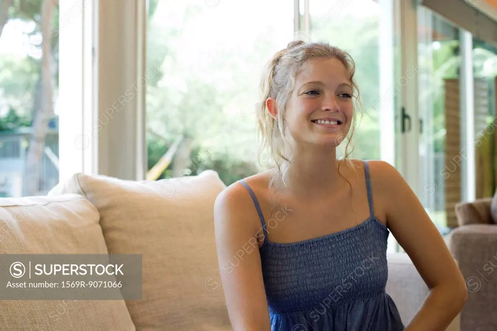 Woman sitting on sofa, smiling